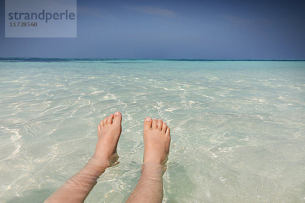 Persönliche Perspektive Barfuß Junge schwimmt in tropischen blauen Ozean