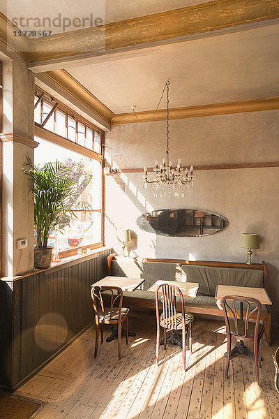 Holztisch mit Stühlen und Stand in leeren Vintage-Café