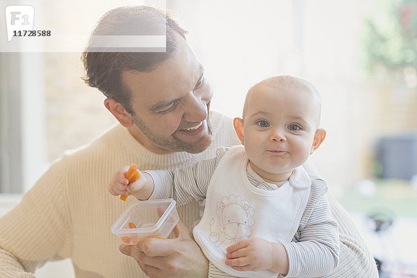 Portrait lächelnd  süßer Sohn und Vater essen Karotten