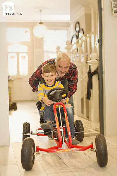 Vater schiebt Sohn auf Spielzeugauto im Foyerflur