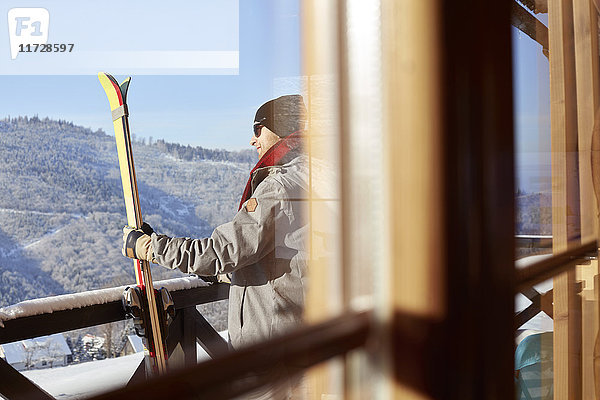 Skifahrer mit Skiern auf sonnigem Hüttenbalkon