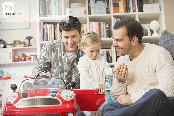 Männliche schwule Eltern und Baby-Sohn spielen mit Spielzeugauto