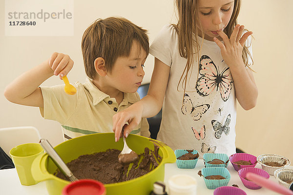 Junge und Mädchen  Bruder und Schwester  machen Schokoladen-Cupcakes  lecken sich die Finger