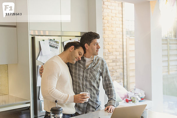 Zärtliches männliches schwules Paar mit Kaffee in der Küche