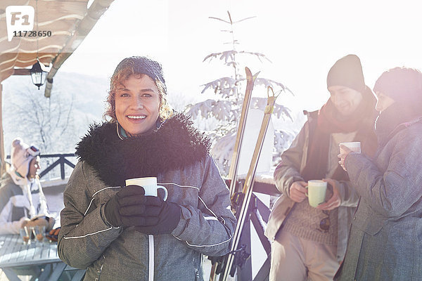Portrait lächelnde Skifahrerin beim Kaffeetrinken auf dem Kabinendeck mit Freunden Apres-Ski