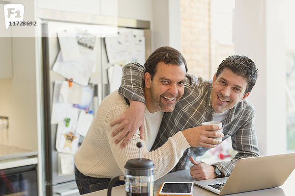 Portrait liebevolle männliche Homosexuell Paar trinken Kaffee und mit Laptop in der Küche