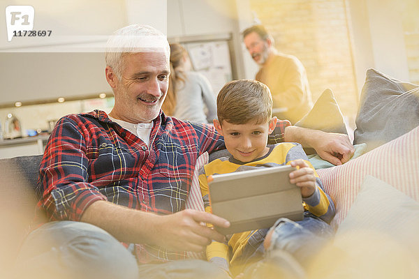 Vater und Sohn verbinden  mit digitalem Tablett auf dem Sofa