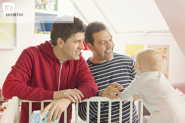 Männliche schwule Eltern beobachten Baby Sohn in der Krippe