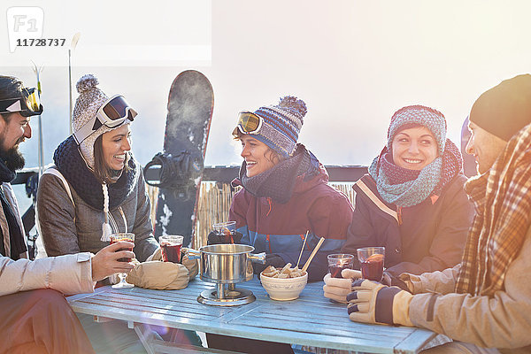 Snowboarderfreunde trinken Cocktails auf dem sonnigen Balkon Apres-Ski