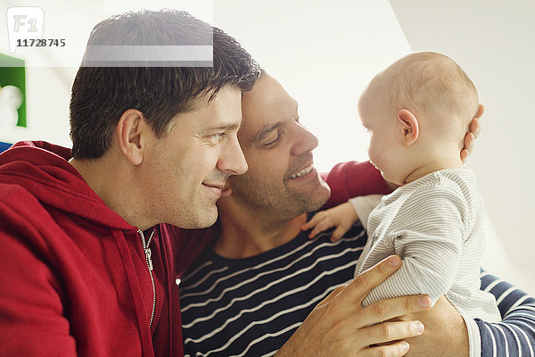Zärtliche männliche schwule Eltern kuscheln Baby-Sohn