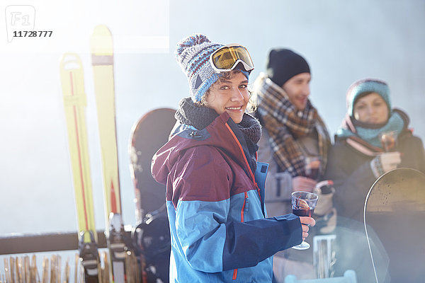 Portrait lächelnde Skifahrerin trinkt Cocktail auf dem Balkon mit Freunden Apres-Ski