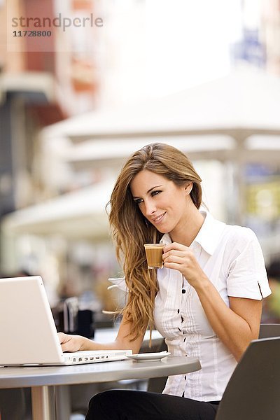 Frau mit Laptop bei einem Kaffee im Freien