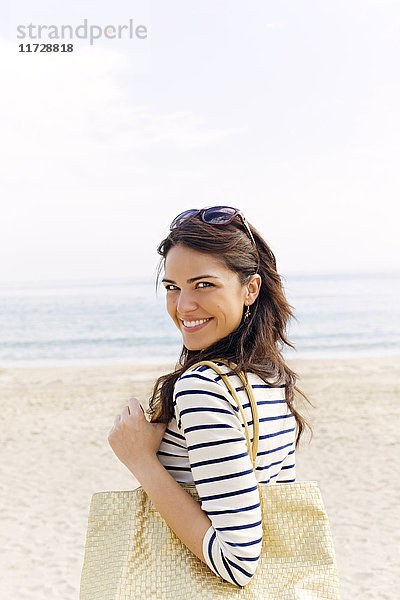 Porträt einer jungen brünetten Frau  die am Strand ankommt