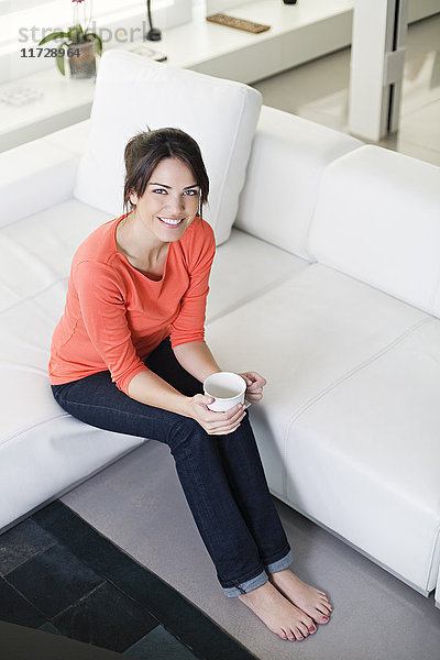 Hübsche Frau mit Kaffee/Tee auf der Couch