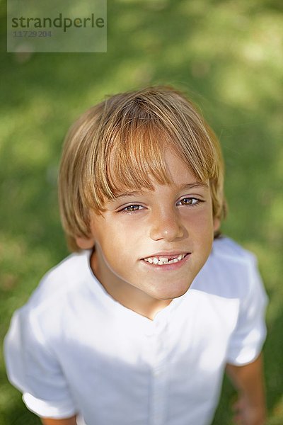 Porträt eines süßen blonden Jungen im Park lächelnd vor der Kamera