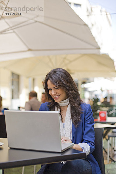 Hübsche brünette Frau mit Laptop im Cafe