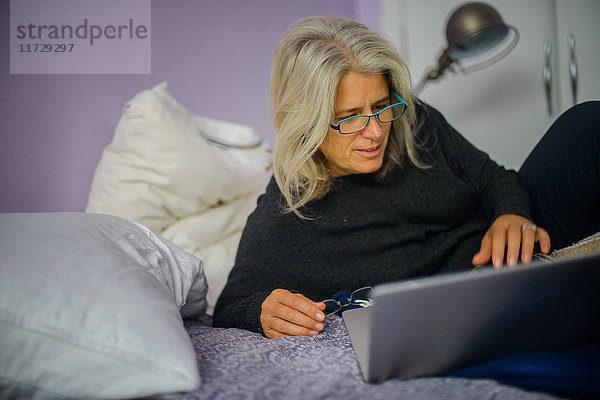 Frau benutzt Laptop im Bett