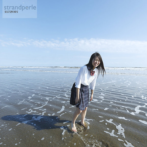 Junge Japanerin in Highschool-Uniform beim Laufen am Meer  Chiba  Japan