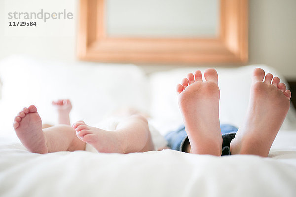 Junges Mädchen und kleiner Bruder auf dem Bett liegend  Fokus auf Füße