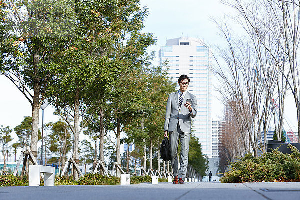 Japanischer Geschäftsmann mit Smartphone in der Innenstadt von Tokio  Japan