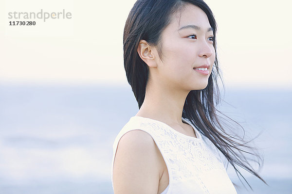 Junge Japanerin in einem weißen Kleid an einer Klippe über dem Meer bei Sonnenaufgang  Chiba  Japan