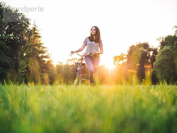 Frau geht Fahrrad auf Gras
