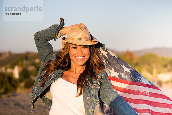 Porträt einer reifen Frau  im Freien  amerikanische Flagge haltend  lächelnd