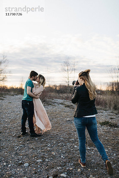 Fotograf  der ein Paar fotografiert  ein Paar  das sich in ländlicher Umgebung küsst