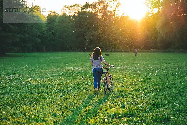 Frau geht Fahrrad auf Gras