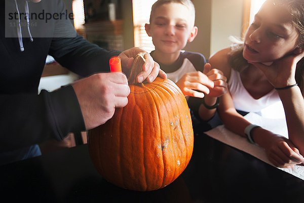 Vater und Kinder schnitzen Kürbis