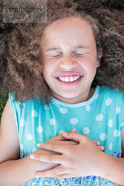 Porträt eines im Gras liegenden Mädchens  lachend  Draufsicht