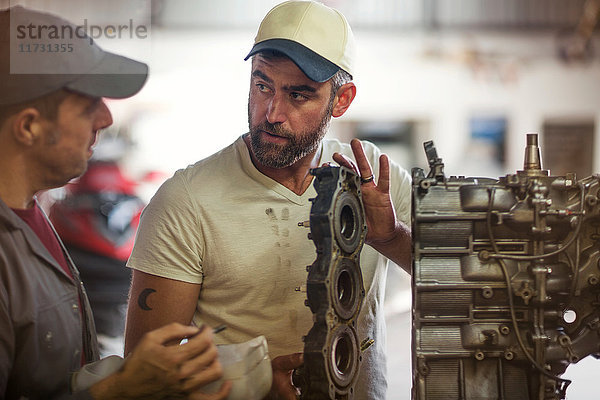 Zwei Männer reparieren Außenbordmotor in Bootsreparaturwerkstatt
