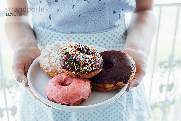 Mittelteil der Frau  die die Platte mit den Donut-Löchern hält