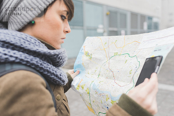 Rucksacktouristin mit Smartphone schaut auf Karte in der Stadt