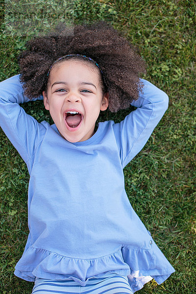 Porträt eines jungen Mädchens im Gras liegend  lachend  Draufsicht