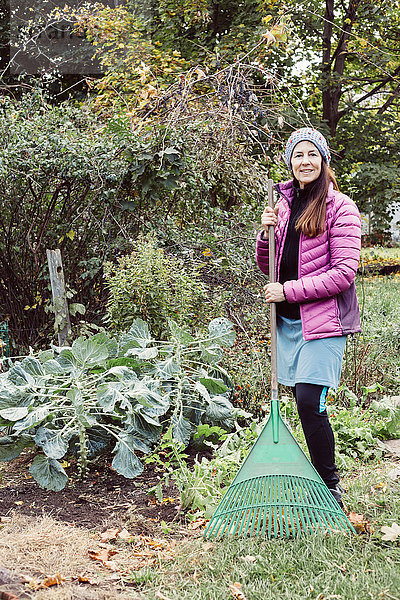 Porträt einer Frau beim Gartenharken