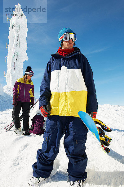 Snowboarder und Skifahrer auf dem Gipfel des Berges mit Ausrüstung  vor einer Eisskulptur