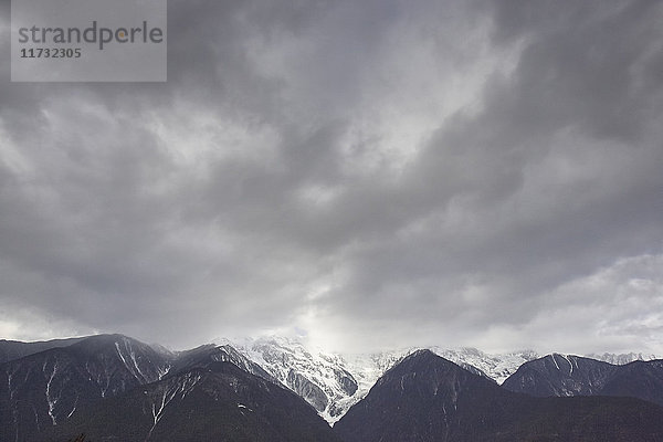 Dramatisch bewölkter Himmel und schneebedeckte Bergkette  Bezirk Shangri-la  Yunnan  China