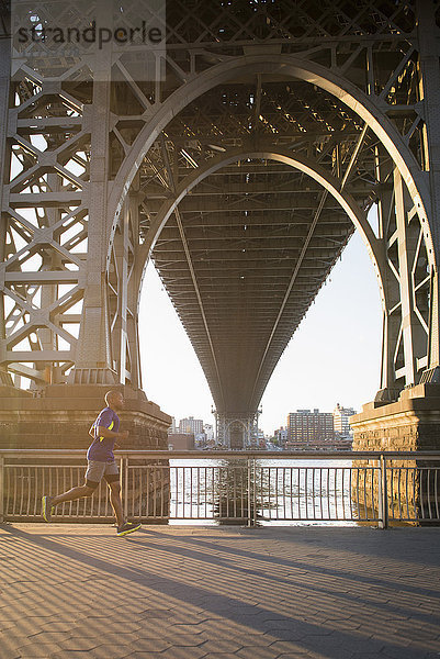 Mann joggt unter der Brücke