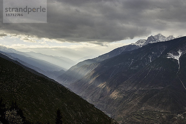 Dramatisch bewölkter Himmel  Sonnenstrahlen auf Bergkette  Bezirk Shangri-la  Yunnan  China