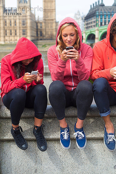 Drei junge Leute schauen auf Mobiltelefone