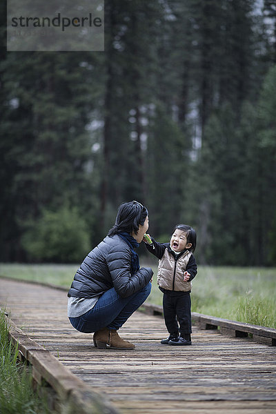 Mittelgroße erwachsene Frau kauert mit ihrer Kleinkind-Tochter auf dem Gehsteig  Yosemite National Park  Kalifornien  USA