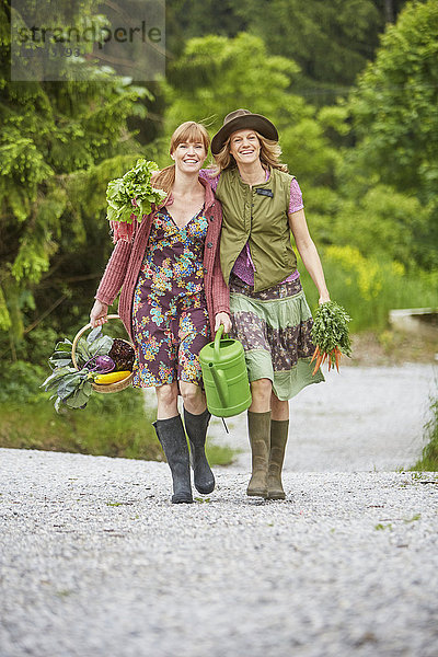 Zwei Frauen tragen Gemüse entlang der Landstraße