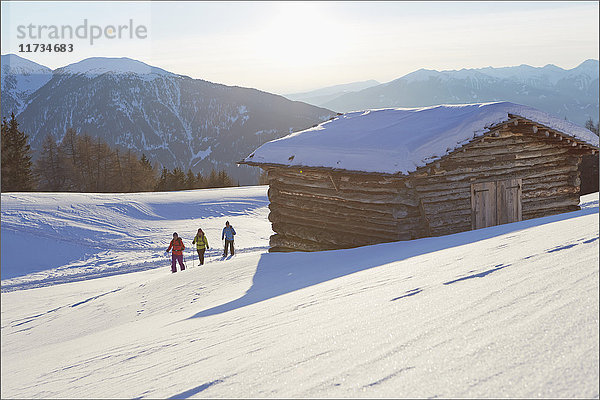 Distanzansicht von drei mitteleuropäischen Freunden beim Schneeschuhwandern in den Dolomiten  Eisacktal  Südtirol  Italien
