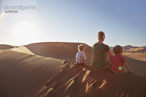 Mutter und Söhne sitzen auf einer Sanddüne  Namib Naukluft Nationalpark  Namib Wüste  Sossusvlei  Dead Vlei  Afrika