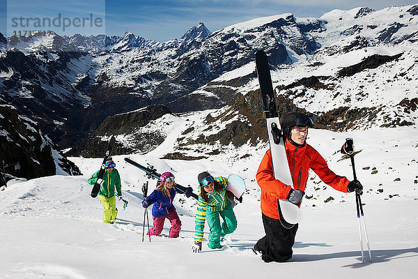 Gruppe von Skifahrern  die mit Skiausrüstung den Berg besteigen