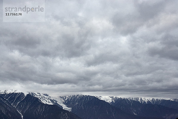 Dramatisch bewölkter Himmel und schneebedeckte Bergkette  Bezirk Shangri-la  Yunnan  China