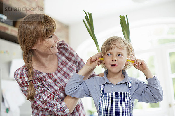 Mutter und Sohn spielen in der Küche mit Gemüse
