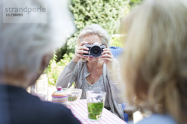 Ältere Frau  die Freunde im Garten fotografiert