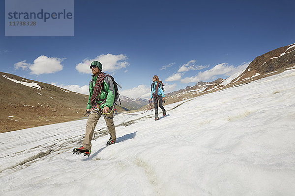 Junges Paar wandert eisabwärts auf dem Schnalstaler Gletscher  Schnalstalstal  Südtirol  Italien